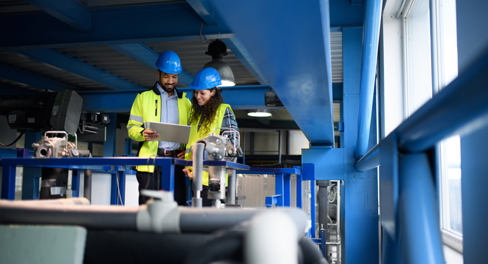 Male and female factory workers looking at tablet computer